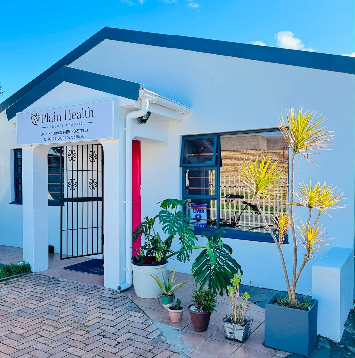 The front of Plain Health General Practice, with its signage and pink front door